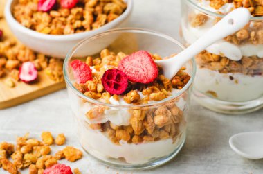 Granola and Yogurt Parfaits, Healthy Breakfast, Muesli with Dried Berries on Bright Concrete Background