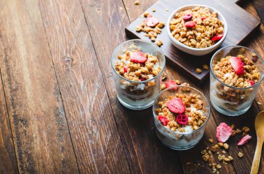 Granola and Yogurt Parfaits, Healthy Breakfast, Muesli with Dried Berries on Dark Wooden Background