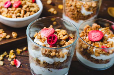 Granola and Yogurt Parfaits, Healthy Breakfast, Muesli with Dried Berries on Dark Wooden Background