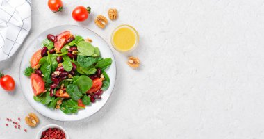 Kırmızı fasulye salatası, ıspanaklı vegan salatası, vişneli domates, ceviz, fasulye ve parlak arkaplanda hardal sosu.