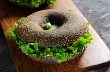 Tahta tahtada salatalıklı ve jambonlu Kara Simitli Sandviçler ve Ahşap Arka plan, Lezzetli Atıştırmalık veya Kahvaltı