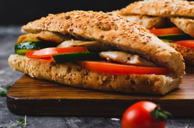 Izgara tavuk ve sebzeli sandviç, sağlıklı ve lezzetli aperatif, kahvaltı, akşam yemeği veya Karanlık Arkaplanda öğle yemeği