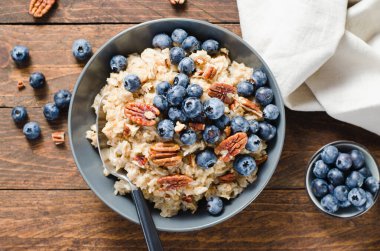 Yulaf ezmesi kasesi, yulaf lapası, yabanmersinli yulaf lapası ve fındıklı kara kırsal arka plan, sağlıklı atıştırmalık veya kahvaltı.