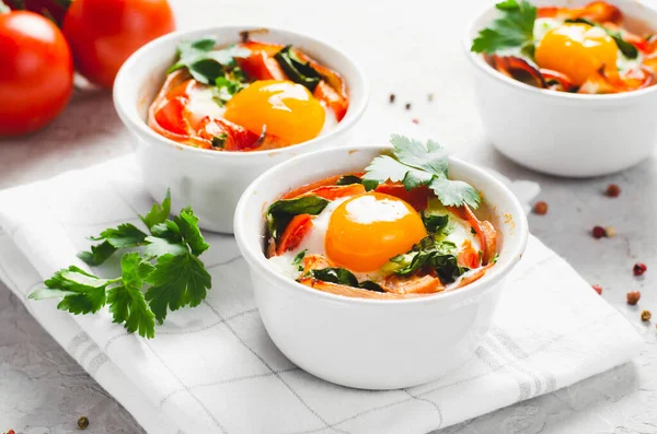 stock image Baked Eggs with Bacon, Tomatoes, Spinach and Herbs on Bright Background, Healthy Rustic Breakfast or Snack