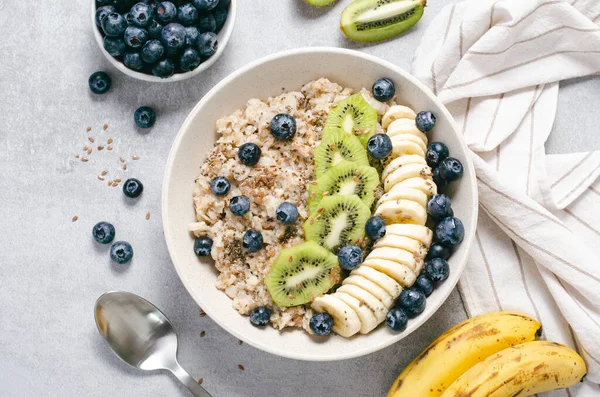 Stock image Oatmeal Bowl, Oat Porridge with Blueberry, Banana and Kiwi on Bright Grey Background, Healthy Snack or Breakfast