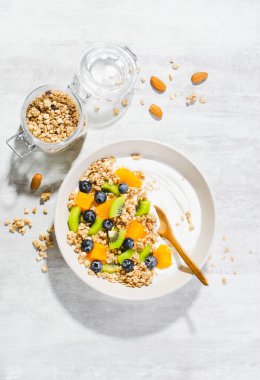 Granola, Kiwi, Yaban mersini ve Portakallı Yoğurt, Sağlıklı Atıştırmalık veya Parlak Arkaplanda Kahvaltı