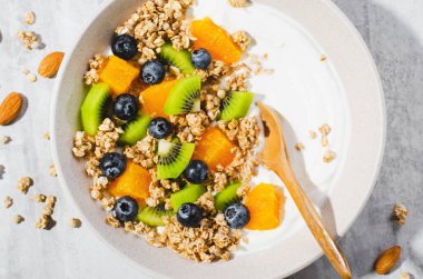 Granola, Kiwi, Yaban mersini ve Portakallı Yoğurt, Sağlıklı Atıştırmalık veya Parlak Arkaplanda Kahvaltı