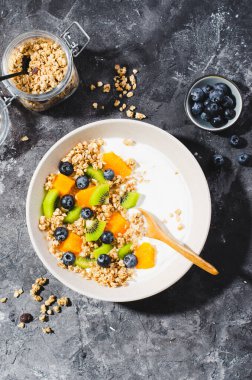 Granola, Kiwi, Yaban mersini ve Portakallı Yoğurt, Sağlıklı Atıştırmalık veya Karanlık Arkaplanda Kahvaltı