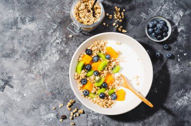 Granola, Kiwi, Yaban mersini ve Portakallı Yoğurt, Sağlıklı Atıştırmalık veya Karanlık Arkaplanda Kahvaltı