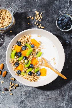 Granola, Kiwi, Yaban mersini ve Portakallı Yoğurt, Sağlıklı Atıştırmalık veya Karanlık Arkaplanda Kahvaltı