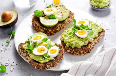 Avokado ve bıldırcın yumurtası tostları, sağlıklı atıştırmalıklar ya da Parlak Arkaplanda Kahvaltı