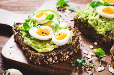 Avokado ve bıldırcın yumurtası tostları, sağlıklı atıştırmalıklar veya tahta arka planda kahvaltı.