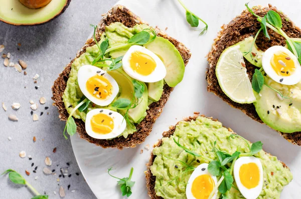 stock image Avocado and Quail Egg Toasts, Healthy Snack or Breakfast on Bright Background