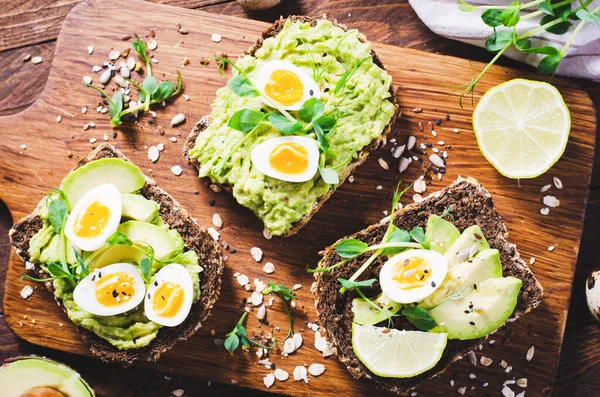 stock image Avocado and Quail Egg Toasts, Healthy Snack or Breakfast on Wooden Background