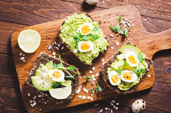 Avokado ve bıldırcın yumurtası tostları, sağlıklı atıştırmalıklar veya tahta arka planda kahvaltı.