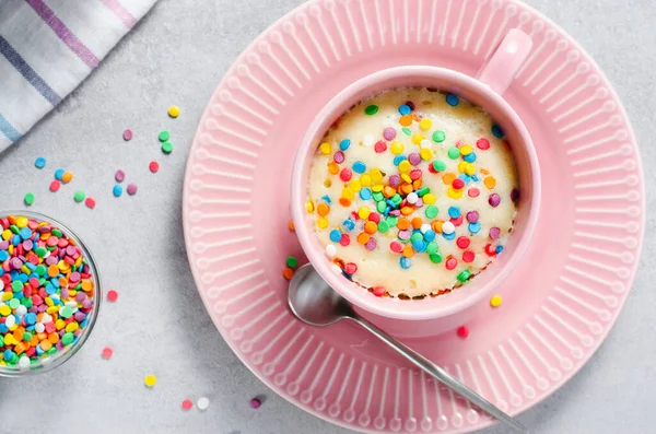 Funfetti Mug Cake, Homemade Cake Cooked in the Microwave on Bright Background