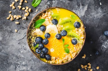 Hindistancevizi kasesinde Orange, Kiwi, Blueberry ve Granola ile Smoothie Bowl, Sağlıklı Yemek, Vegan veya Vejetaryen Beslenme Konsepti