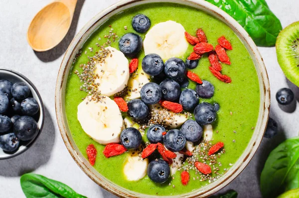 stock image Healthy Green Smoothie in a Bowl with Banana, Blueberry, Goji, and Chia Seed Toppings, Detox, Vegan or Vegetarian Food on Bright Background