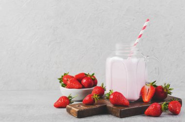 Çilekli içecek, milkshake ve açık gri arka planda taze çilek.