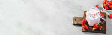 Çilekli içecek, milkshake ve açık gri arka planda taze çilek.