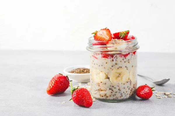 Overnight Oats with Fresh Strawberry, Banana and Chia Seeds in Jars on Grey Background, Healthy Snack or Breakfast