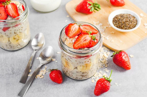 Stock image Overnight Oats with Fresh Strawberry, Banana and Chia Seeds in Jars on Grey Background, Healthy Snack or Breakfast