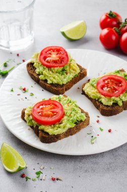 Domatesli Avokado Tostları, Sağlıklı Atıştırmalıklar ya da Açık Gri Arkaplanda Kahvaltı