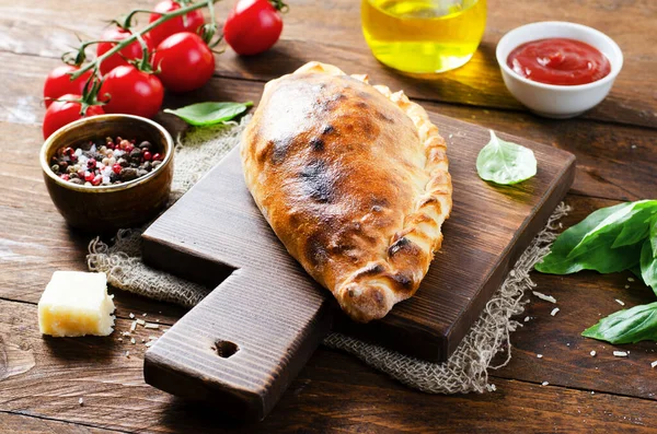 stock image Delicious Pizza Calzone, Traditional Italian Pizza with Tomatoes and Fresh Basil on Wooden Rustic Background