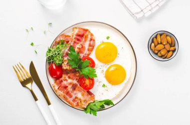 Kızarmış yumurta ve pastırma ile vişneli domates tabakta, kahvaltıda, Keto 'da, Paleo diyetinde parlak arka planda.