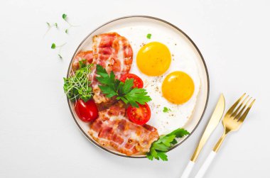 Kızarmış yumurta ve pastırma ile vişneli domates tabakta, kahvaltıda, Keto 'da, Paleo diyetinde parlak arka planda.