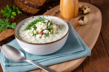 Cold Okroshka Soup with Eggs, Vegetables, Meat, Herbs and Kefir on a Wooden Rustic Background, Summer Soup clipart