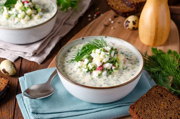 stock image Cold Okroshka Soup with Eggs, Vegetables, Meat, Herbs and Kefir on a Wooden Rustic Background, Summer Soup