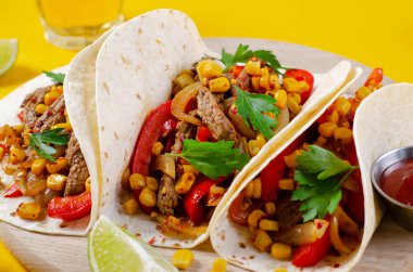 Meksika tacoları, sığır eti ve sebzeli, Tacos al Pastor, parlak sarı arka planda.