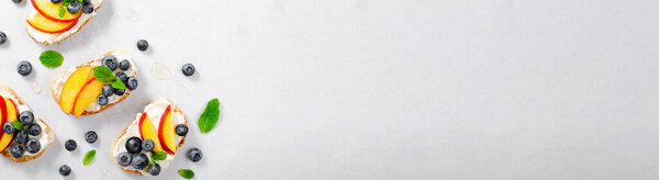 Домашний тост с черникой, персиком и сливочным сыром, вкусные закуски или завтрак на ярком фоне