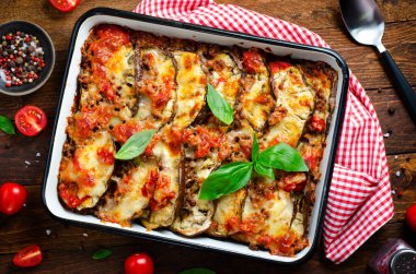 Patlıcan güveci, kıymalı kızarmış patlıcan tabağı, domates sosu ve ahşap arka planda Mozzarella.