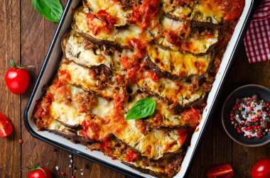 Patlıcan güveci, kıymalı kızarmış patlıcan tabağı, domates sosu ve ahşap arka planda Mozzarella.