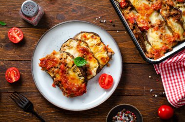 Patlıcan güveci, kıymalı kızarmış patlıcan tabağı, domates sosu ve ahşap arka planda Mozzarella.