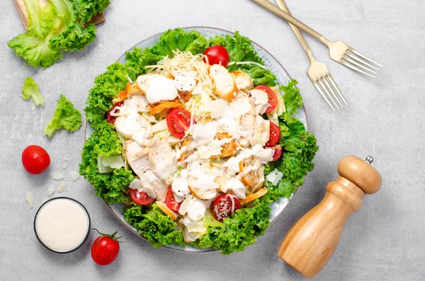 stock image Caesar Salad, Fresh Salad with Grilled Chicken Breast, Croutons, Parmesan Cheese, Cherry Tomatoes, Lettuce and Dressing over Bright Concrete Background