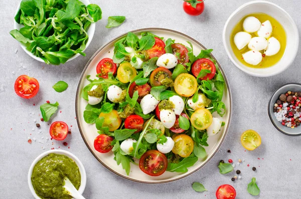 stock image Caprese Salad with Cherry Tomatoes and Pesto Sauce over Bright Concrete Background