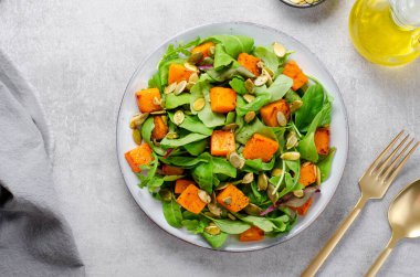 Arugula ve Balkabağı tohumlu balkabağı salatası, Kızarmış balkabağı salatası, Beton Arka planda Taze Vegan Sonbahar Salatası