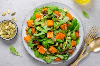Arugula ve Balkabağı tohumlu balkabağı salatası, Kızarmış balkabağı salatası, Beton Arka planda Taze Vegan Sonbahar Salatası