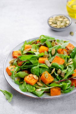 Arugula ve Balkabağı tohumlu balkabağı salatası, Kızarmış balkabağı salatası, Beton Arka planda Taze Vegan Sonbahar Salatası