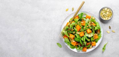 Arugula ve Balkabağı tohumlu balkabağı salatası, Kızarmış balkabağı salatası, Beton Arka planda Taze Vegan Sonbahar Salatası