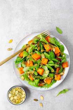 Arugula ve Balkabağı tohumlu balkabağı salatası, Kızarmış balkabağı salatası, Beton Arka planda Taze Vegan Sonbahar Salatası