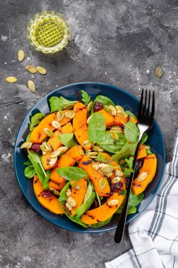 Arugula, ıspanak ve balkabağı tohumlu ızgara balkabağı salatası, kavrulmuş balkabağı salatası, arka planda sonbahar salatası.