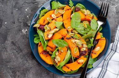 Arugula, ıspanak ve balkabağı tohumlu ızgara balkabağı salatası, kavrulmuş balkabağı salatası, arka planda sonbahar salatası.