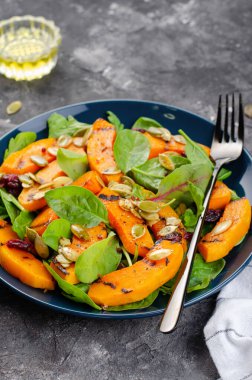 Arugula, ıspanak ve balkabağı tohumlu ızgara balkabağı salatası, kavrulmuş balkabağı salatası, arka planda sonbahar salatası.