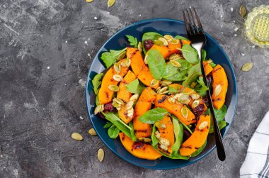 Arugula, ıspanak ve balkabağı tohumlu ızgara balkabağı salatası, kavrulmuş balkabağı salatası, arka planda sonbahar salatası.