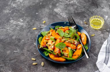 Arugula, ıspanak ve balkabağı tohumlu ızgara balkabağı salatası, kavrulmuş balkabağı salatası, arka planda sonbahar salatası.