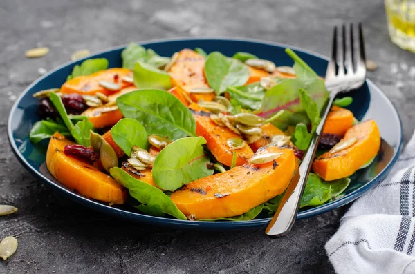 Grilled Pumpkin Salad with Arugula, Spinach, and Pumpkin Seeds, Salad Mix with Roasted Pumpkin, Autumn Salad on Dark Background